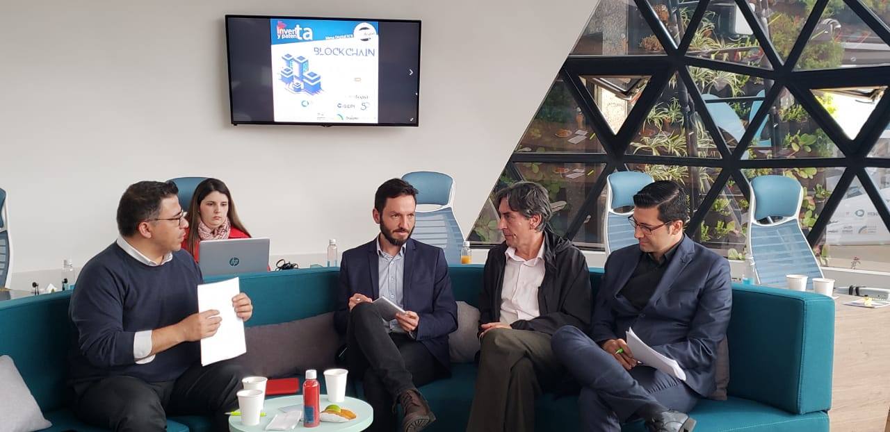 hombres sentados hablando de de blockchain en la cúpula de Grupo Bolivar Creategia Invita